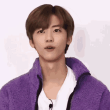 a young man wearing a purple jacket and a white shirt .