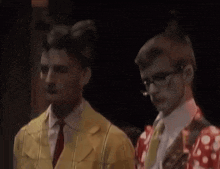 two men are standing next to each other and one is wearing a yellow jacket
