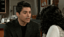 a man in a suit talks to a woman in a white top