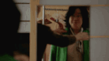 a woman in a green jacket is smiling at herself in a mirror