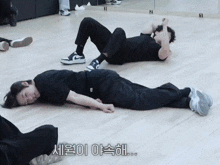 two men are laying on their stomachs on a wooden floor with korean writing on the floor