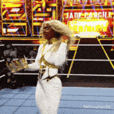 a woman in a white and gold outfit is dancing in a wrestling ring in front of a sign that says jade cargill