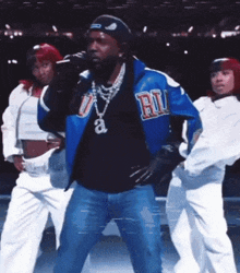 a man in a blue jacket with the letter r on it is singing into a microphone .