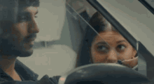 a man is driving a car with a woman looking out of the window