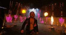 a man without a shirt is walking on a stage with flames coming out of the ceiling .