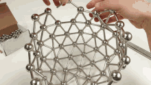 a person is playing with a metal structure with balls and sticks