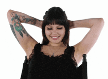 a woman with tattoos on her arm holds her hands behind her head