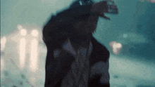 a man wearing headphones and a hat stands in the rain