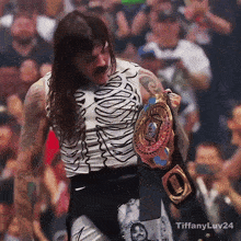 a wrestler is holding a championship belt in front of a crowd with tiffanyluv24 written on the bottom right