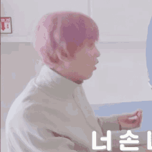 a man with pink hair is sitting in front of a sign that says ' emergency exit '