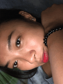 a woman wearing a pearl earring and a black pearl necklace