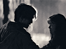 a man and a woman looking at each other in a black and white photo