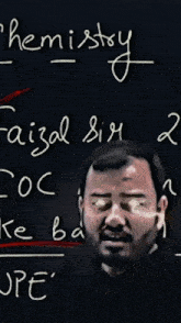 a man with glasses stands in front of a blackboard with the word chemistry written on it