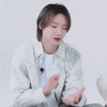 a young man in a striped shirt is sitting at a table with his eyes closed and holding something in his hands .