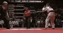 a man in a karate uniform is fighting another man in a karate tournament .