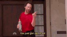 a man in a red shirt is holding a bottle of alcohol .
