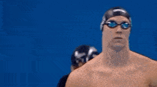 a man wearing a swimming cap and goggles is standing in front of a blue wall .