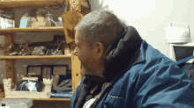 a man in a blue jacket is sitting in front of a wooden shelf