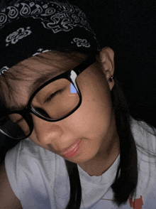 a girl wearing glasses and a bandana has a blue triangle on her eye