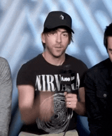 a man wearing a nirvana t-shirt holds a microphone