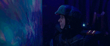 a man wearing a helmet and gloves is pointing at a screen