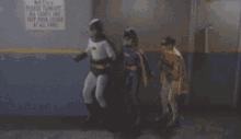 batman and batgirl are standing in front of a sign that says all lights and keep door locked at all times