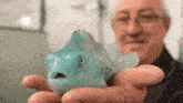a man is holding a blue fish in his hands