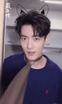 a young man wearing a cat ear headband looks at the camera