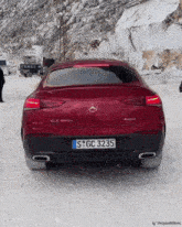 a red mercedes is parked in the snow