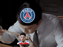 a man is eating rice with chopsticks with a paris saint germain logo on his head