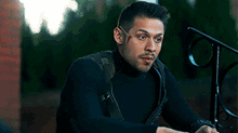 a man in a black turtleneck sweater is sitting on a staircase .