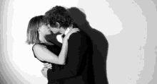 a man and woman kissing in front of a white wall