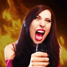 a woman is singing into a microphone with her mouth open