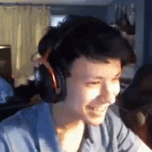 a young man wearing headphones is smiling while sitting at a desk .