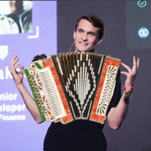 a man is holding an accordion in front of a screen that says junior developer
