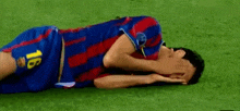 a soccer player with the number 18 on his shorts is laying on the grass with his head in his hands .