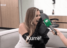 a woman wearing a white dress and black gloves is being interviewed by someone holding a green microphone and says kurre