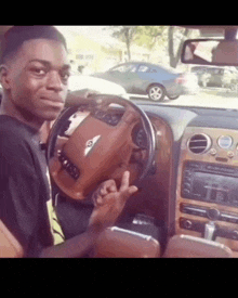 a young man is sitting in a bentley car and giving the middle finger