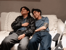 two men are sitting on a couch with one wearing a shirt that says ' xxiv '