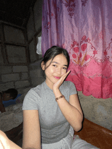 a girl sitting in front of a pink and purple curtains