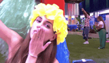 a woman wearing a yellow flower headband blows a kiss