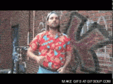 a man in a red shirt is dancing in front of a brick wall