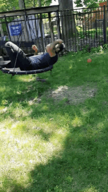 a person is laying on a swing in a park with a sign that says " no smoking "