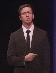 a man in a suit and tie is pointing