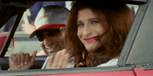 a man wearing a castrol hat is driving a car with a woman