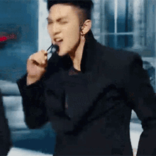 a man in a black jacket is singing into a microphone with a stick in his mouth