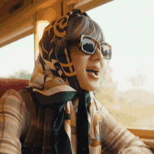 a woman wearing sunglasses and a scarf around her head with the letter e on it
