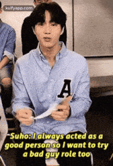 a young man in a blue shirt with the letter a on it is sitting in a room .