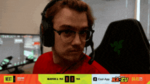 a man wearing headphones and a red shirt is sitting in front of a computer monitor