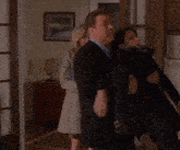 a man in a suit is carrying a woman in a black coat